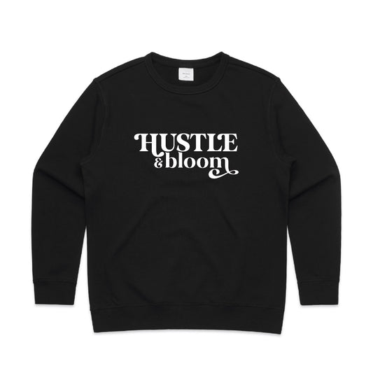 Black crew neck jumper with white text stating "Hustle and Bloom"